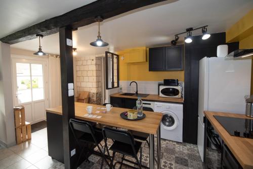 une cuisine avec une table et un réfrigérateur dans l'établissement Domaine des Demoiselles - Gîte et Spa, à Hauteville