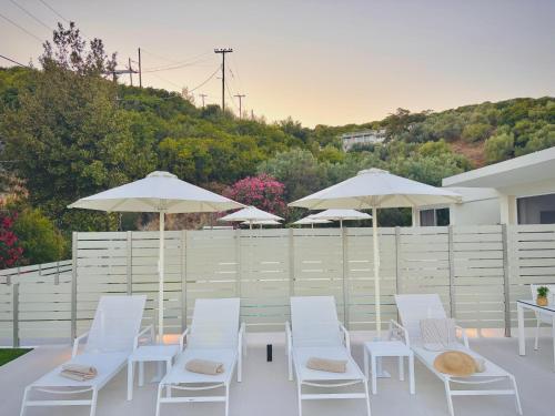 a group of white chairs and tables and umbrellas at Zorbas Family Villas in Skiathos Town