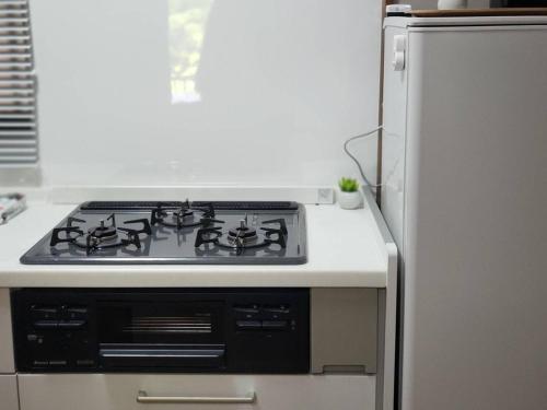 a stove top oven in a kitchen next to a refrigerator at ヴィラリバーサイド in Takamatsu