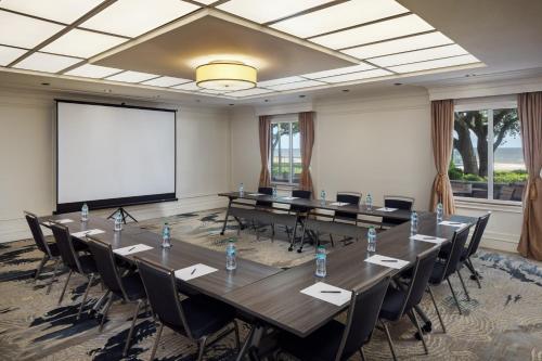 a conference room with tables and chairs and a projection screen at The Inn at Long Beach in Long Beach