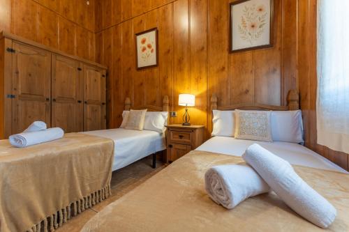 two beds in a room with wooden walls at Casa con piscina Jailás in Valverde de Mérida