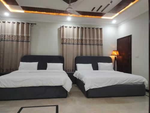 two beds sitting in a room with curtains at The Guest House Islamabad in Islamabad