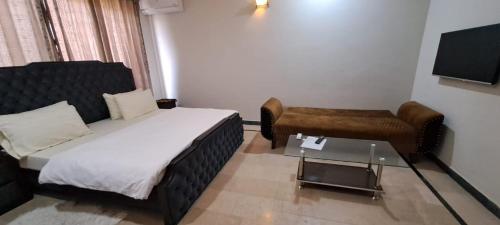 a bedroom with a bed and a couch and a table at The Guest House Islamabad in Islamabad