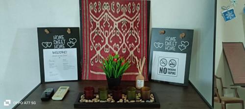 a room with a table with a flower arrangement and signs at Green Tree Homestay in Miri