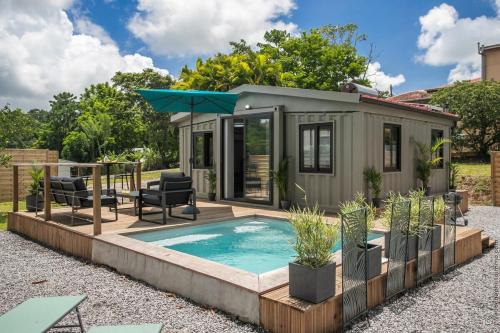 a tiny house with a pool and a patio at Éco-Chic Bungalow by Bungazur in Saint-Joseph