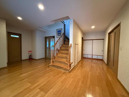 an empty room with wooden floors and a staircase at 越前シーサイドゲストハウス オーシャンズ Echizen Seaside Guesthouse OCEAN'S in Fukui