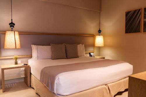 a bedroom with a large white bed with two lamps at Hotel Santa Cecilia B&B in Cartagena de Indias