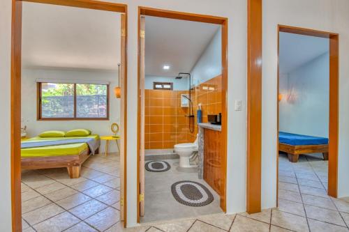 a bathroom with a shower and a toilet and a bedroom at Oceanfront House with AC, Fast WiFi at Cocles Beachbreak in Puerto Viejo