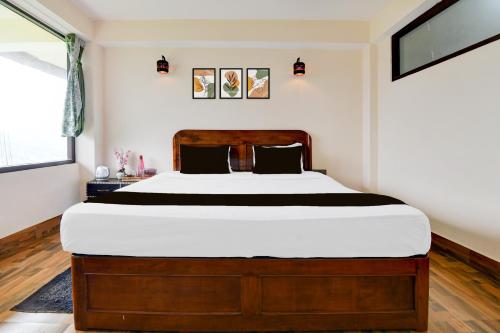 a bedroom with a large bed with a wooden headboard at Hotel O Ranka Gangtok in Tādong