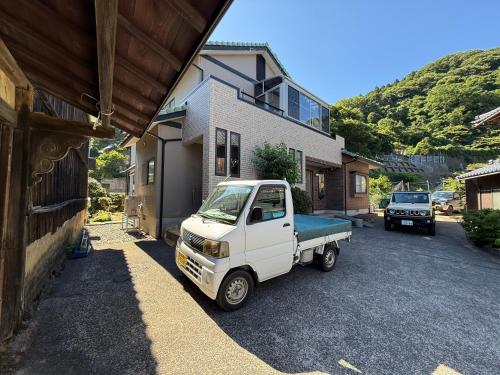 a white truck parked in front of a house at 越前シーサイドゲストハウス オーシャンズ Echizen Seaside Guesthouse OCEAN'S in Fukui