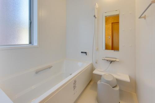 a white bathroom with a tub and a mirror at Gotemba Kogen Tokinosumika in Gotemba