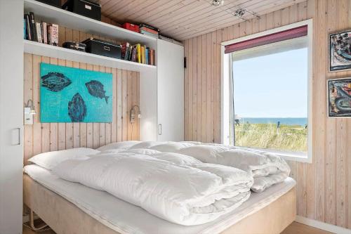 Bett in einem Zimmer mit Fenster und Bücherregal in der Unterkunft 755 Hvide Sande - Søndergade 106 in Hvide Sande