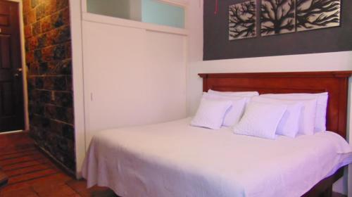 a bedroom with a bed with white sheets and pillows at Hotel del Centro in Bernal