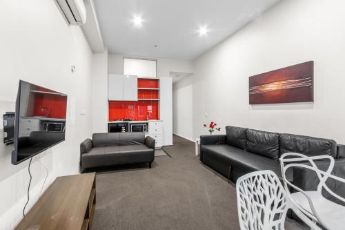 a living room with a couch and a table at Comfort Apartments on Elizabeth in Melbourne