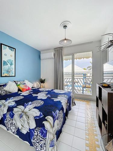 a blue bedroom with a bed and a balcony at Studio Coin Du Bonheur in Saint-François