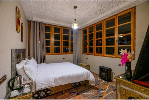 a bedroom with a white bed and some windows at Riad Atlas Bangalow in Imlil