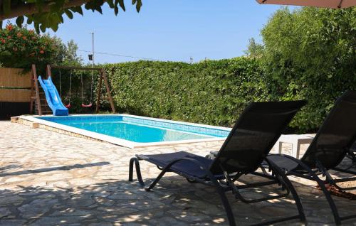 a swimming pool with two chairs and a slide at Two-Bedroom Holiday Home In Sibenik in Šibenik