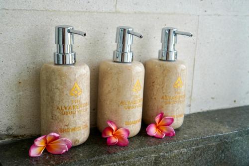 three bottles of disinfectants sitting on a counter with flowers at The Alvarendra Ubud Villa By Bali Cabin in Ubud