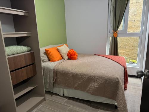 a bedroom with a bed with orange pillows on it at Mirador Santo Tomás - Moderno a minutos de Antigua in Santa Lucía Milpas Altas
