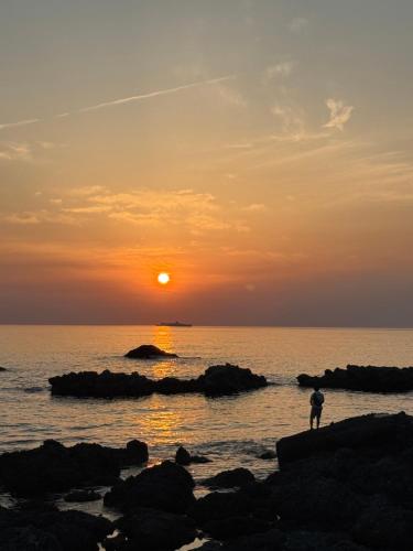 a person standing on the beach watching the sunset at 越前シーサイドゲストハウス オーシャンズ Echizen Seaside Guesthouse OCEAN'S in Fukui