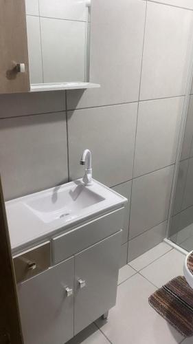 a white bathroom with a sink and a mirror at Pousada Vale das Pedras 03 in Pedras Grandes