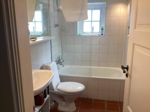 a bathroom with a tub and a toilet and a sink at 4 star holiday home in Humlebæk in Humlebæk