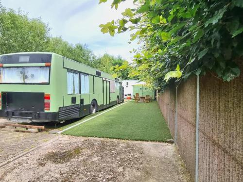 a green bus parked in a yard next to a fence at Luxury tiny house with sauna in Lierneux in Lierneux