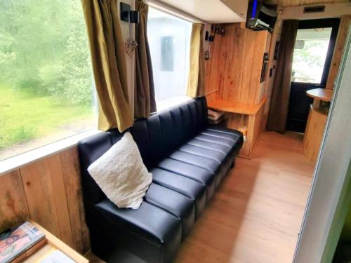 a black leather couch in a room with a window at Luxury tiny house with sauna in Lierneux in Lierneux