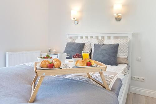 ソポトにあるApartament Aquarius Sopotのベッドの上にフルーツとドリンクを用意した朝食トレイ