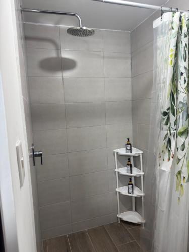 a shower with a white shower curtain and a white shelf at Mirador Santo Tomás - Moderno a minutos de Antigua in Santa Lucía Milpas Altas