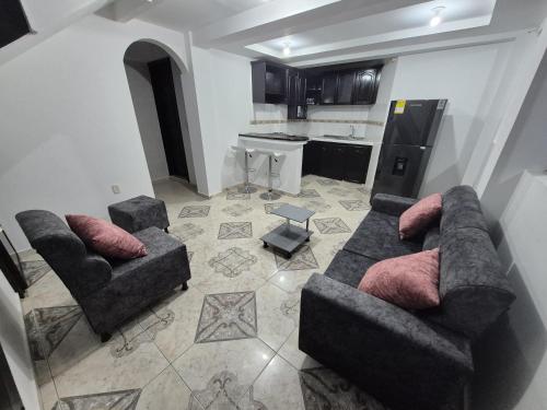 a living room with two couches and a kitchen at Hotel El Buen Descanso in Filandia