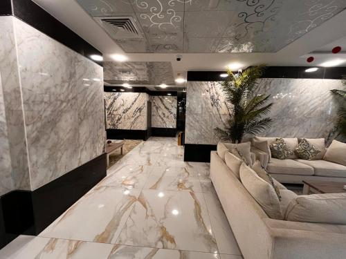 a living room with white marble floors and couches at Aryaf Hotel Apart Tabasum Group in Ajman 