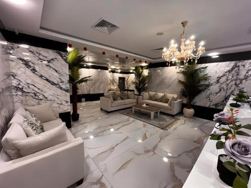 a living room with white furniture and a marble wall at Aryaf Hotel Apart Tabasum Group in Ajman 