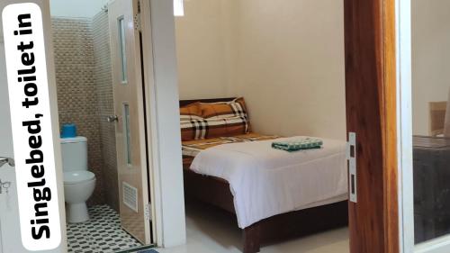 a small bedroom with a bed and a toilet at Harmony Resto & Homestay in Ngadisari