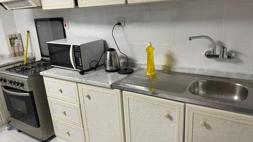a kitchen with a microwave and a sink at Book A bed Hostel in Dubai