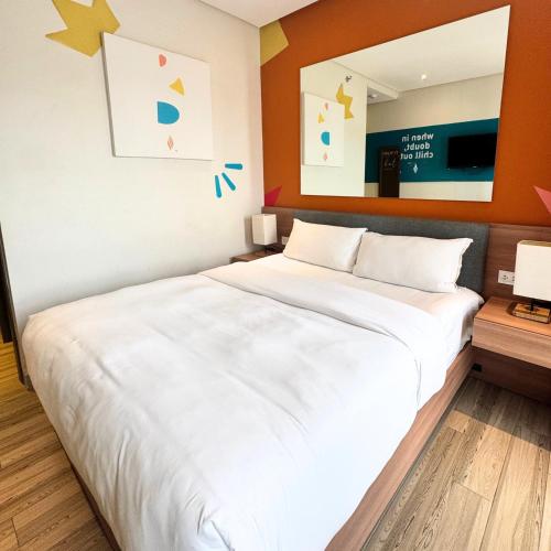 a bedroom with a large white bed with a mirror at Luxebridge Hotel in Davao City