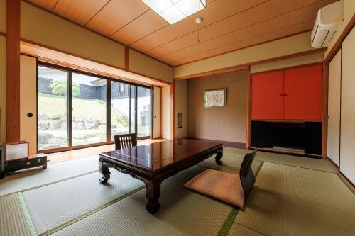 a living room with a wooden table and a large window at Hotel Kikori in Hida