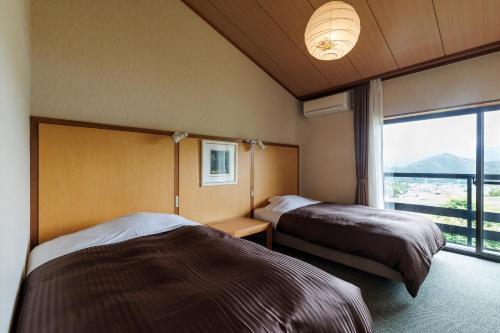 a hotel room with two beds and a large window at Hotel Kikori in Hida
