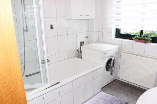 biała łazienka z wanną i pralką w obiekcie Casa Clara w mieście Kleve