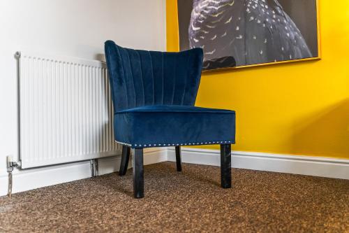 a blue chair sitting next to a yellow wall at Cosy 3-bedroom house, garden, fast wi-fi, 6 mins walk to Hull fair, 4 mins drive to MKM stadium perfect for Contractors, Families, HRI hospital locum staff and corporate guests in Hull