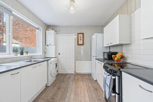 a white kitchen with white appliances and a window at Cosy 3-bedroom house, garden, fast wi-fi, 6 mins walk to Hull fair, 4 mins drive to MKM stadium perfect for Contractors, Families, HRI hospital locum staff and corporate guests in Hull
