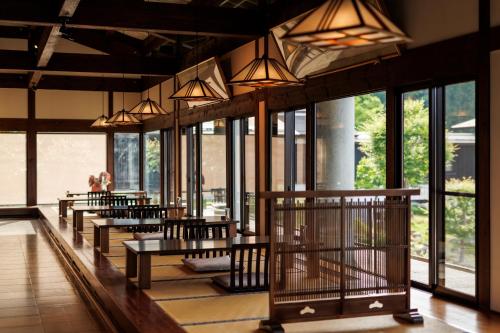 a row of tables and chairs in a room with windows at Hotel Kikori in Hida
