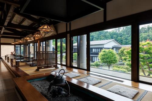 a room with large windows and a table with a tea kettle at Hotel Kikori in Hida