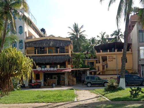 a building with palm trees in front of it at Hotel Papaya Surf in Puerto Escondido