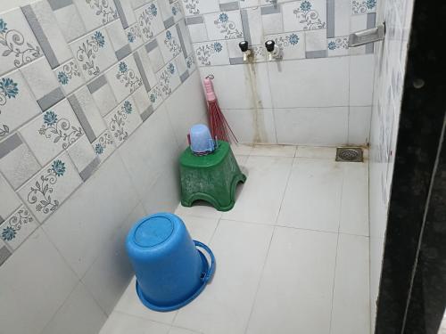 a small bathroom with a shower and a green stool at JAI SWAMiNARAYAN DELUX HOMESTAY in Garudeshwar