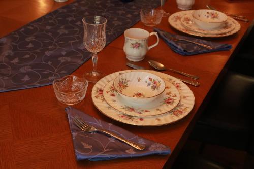 a wooden table with plates and cups and utensils at A Garden Stroll Bed & Breakfast in Stratford