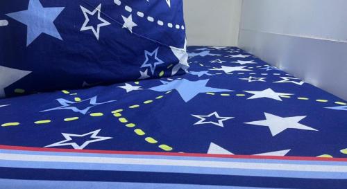 a bed with a blue blanket with stars on it at Book A bed Hostel in Dubai