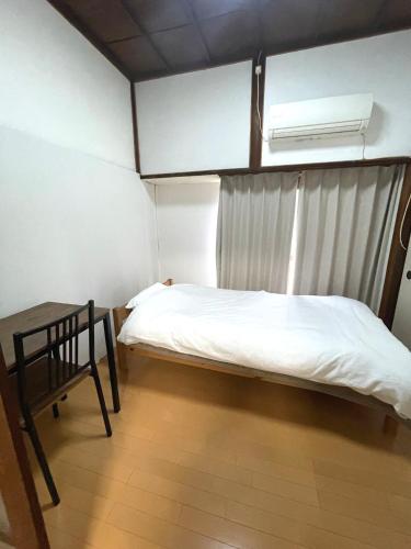 a bedroom with a bed and a chair and a window at 懐かしい日本の家 nostalgic Japanese house For-R Uwamachi Share House in Yokosuka