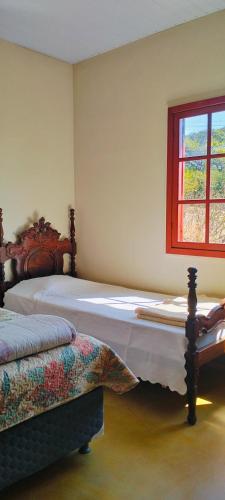 una camera da letto con due letti e una finestra di Casa das Mangueiras no Largo da Matriz de São Gonçalo do Rio das Pedras a Sêrro
