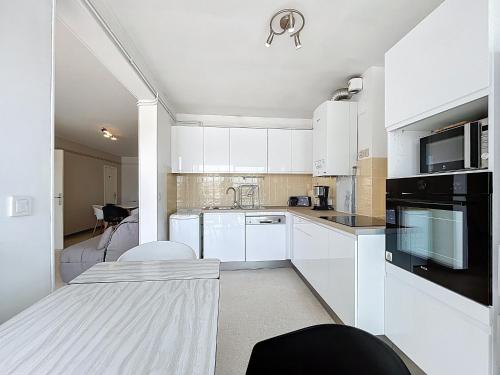 - une cuisine blanche avec des placards blancs et une table dans l'établissement Appartement T2 avec piscine, tennis, proche port et plage, 4 couchages, Carnon - FR-1-715-33, à Mauguio